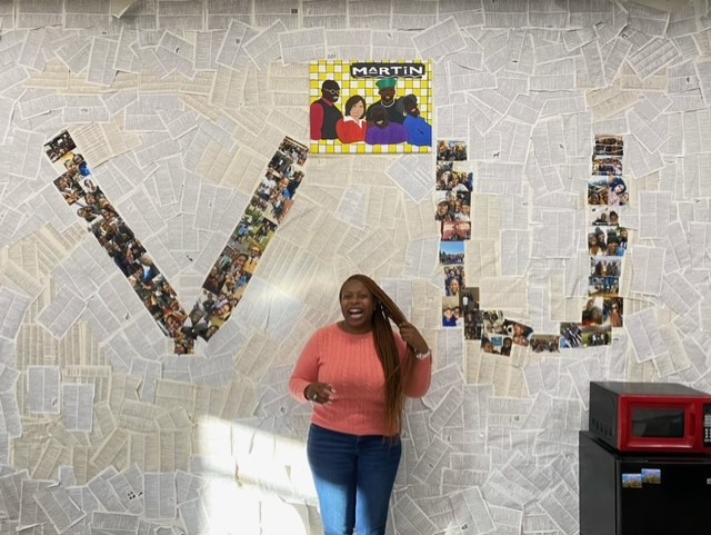 Ms. Jahara Davis in front of lots of pictures of her with loads of different hairstyles throughout the years.